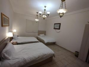 a bedroom with two beds and a chandelier at Qurban Apartment in Al ‘Awālī