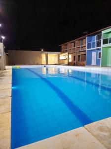 uma grande piscina azul à noite em Casa na Praia com Super Piscina, em Condomínio Fechado. em São José de Ribamar