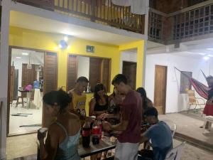 um grupo de pessoas em pé em torno de uma mesa em uma sala em Casa na Praia com Super Piscina, em Condomínio Fechado. em São José de Ribamar