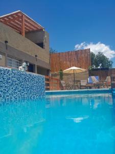 una piscina de agua azul frente a una casa en Rincon de las sierras en Villa Carlos Paz