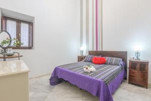 Schlafzimmer mit einem Bett mit lila Bettwäsche und roten Kissen in der Unterkunft GALINDO CENTER PREMIUM SUITES, Free Parking in Sevilla