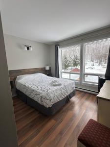 a bedroom with a bed and a large window at Auberge Morritt in Mont-Tremblant