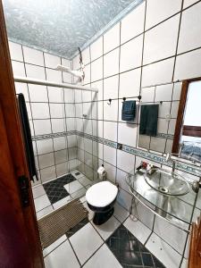 a white tiled bathroom with a toilet and a sink at Pousada Costa Azul in Barra Grande