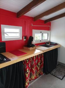 eine Küche mit roten Wänden und einer Theke mit einer Spüle in der Unterkunft Haut de villa dans le nord de la grande terre (Guadeloupe). in Anse-Bertrand