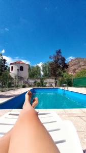 a man laying on a chair next to a swimming pool at El Torreón Lodge in Potrerillos
