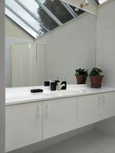 a white bathroom with a sink and a mirror at Amazing Lakeview Loft in Rotorua