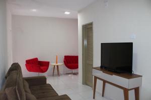 ein Wohnzimmer mit einem Sofa und einem Flachbild-TV in der Unterkunft Pousada Oásis do Cariri in Juazeiro do Norte