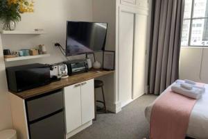 a room with a bed and a desk with a television at Cute Heritage Studio , Pools and Gym! in Auckland