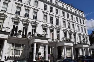 a large white building with white columns and windows at Kensington Apartments in London