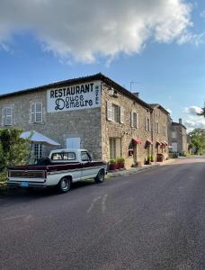 an old car parked in front of a brick building at Douce Demeure in Mortemart