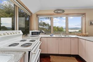 a kitchen with a stove and a sink and windows at Snowgums on the Lake in Jindabyne