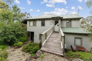 a house with a wooden ramp leading up to it at Snowgums on the Lake - Charming 4BR Home l Amazing Lake Views l Balcony in Jindabyne