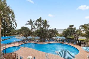 a large swimming pool with umbrellas and chairs at The Rocks Resort 1C in Gold Coast