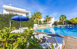 einen Pool mit Stühlen und einem blauen Sonnenschirm in der Unterkunft Awesome Home In Marina Di Ragusa in Marina di Ragusa + 28 Fotos