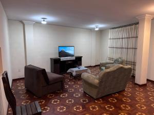 a living room with two chairs and a flat screen tv at Departamentos a su altura en La Paz in La Paz