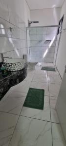 a white bathroom with a toilet and a green rug at Iguassu Jungle pousada in Foz do Iguaçu