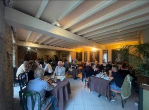 a group of people sitting at tables in a restaurant at Douce Demeure in Mortemart