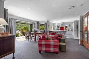 a living room with a red couch and a kitchen at Elite Holiday Homes Queenstown - Arrowbrae in Arrowtown