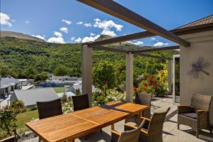 - une table et des chaises en bois sur une terrasse avec vue dans l'établissement Elite Holiday Homes Queenstown - Arrowbrae, à Arrowtown