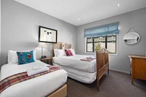 1 dormitorio con 2 camas y ventana en Elite Holiday Homes Queenstown - Arrowbrae, en Arrowtown