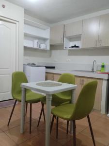 une cuisine avec une table blanche et des chaises vertes dans l'établissement Kara's Suite, à Cebu