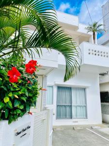una casa blanca con flores rojas delante en Sunset Beach House, en Chatan