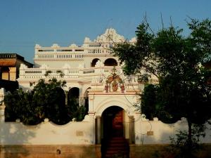 Un grand bâtiment blanc avec un escalier se trouve devant. dans l'établissement Saratha Vilas Chettinad, à Kānādukāttān