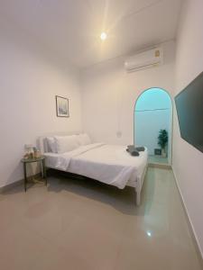 a white bedroom with a bed and a mirror at STAYDII serviced residence Chaengwattana in Pak Kret