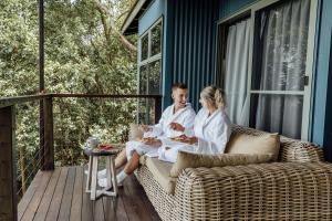 Ein Mann und eine Frau sitzen auf einer Couch auf einer Veranda in der Unterkunft Treetops Seaview Montville in Montville