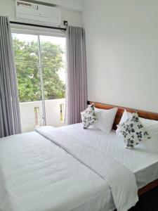 Un dormitorio con una cama blanca con almohadas y una ventana. en RKO Villa27 - Unawatuna, en Habaraduwa Central