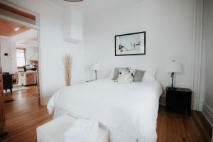 um quarto branco com uma grande cama branca com almofadas em Le Patrimonial em Sainte-Agathe-des-Monts