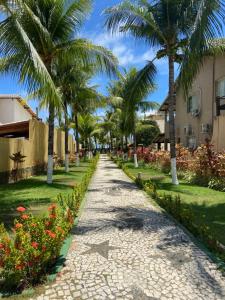 brukowana ulica z palmami i kwiatami w obiekcie Guarajuba - casa em condomínio corais a 200 metros da praia w mieście Camaçari