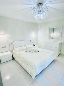 - une chambre blanche avec un lit et un lustre dans l'établissement Spacious apartment in the center of Nice near the sea, à Nice