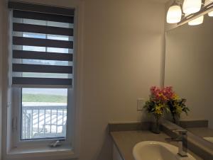 鮑曼維爾的住宿－Honey Dew，一间带水槽的浴室和一个带百叶窗的窗户