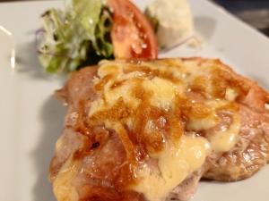 ein Stück Fleisch mit Käse auf einem Teller mit Salat in der Unterkunft Silver Shiga in Yamanouchi + 19 Fotos
