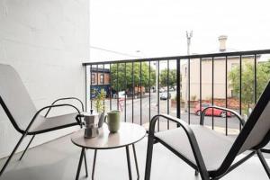 a balcony with two chairs and a table with a view of a street at CBD Apartment with WiFi & Parking in Launceston