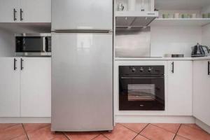 CBD Apartment with WiFi & Parking في لونسيستون: مطبخ فيه دواليب بيضاء وفرن