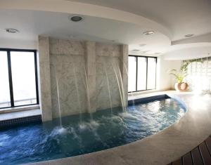 a swimming pool in a building with windows at Harmonia Flat's - Aeroporto Gru in Guarulhos