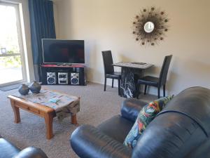 a living room with a leather couch and a table at Highview Drive Apartment in Nelson