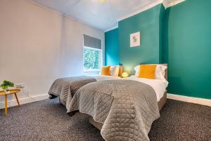 a bedroom with two beds and a blue wall at Comfy Contractor Stay in Stoke - Free Parking in Stoke on Trent