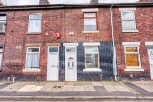 a brick building with white doors on a street at Comfy Contractor Stay in Stoke - Free Parking in Stoke on Trent