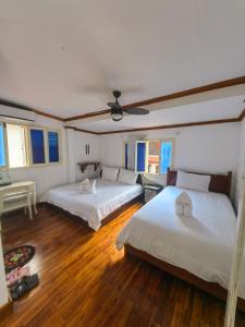 2 Betten in einem Zimmer mit Holzböden in der Unterkunft 左岸小筑 in Luang Prabang