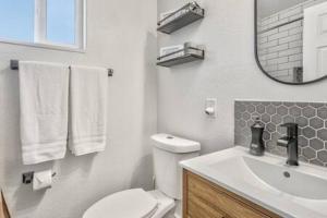 a bathroom with a toilet and a sink and a mirror at Vibrant Watermelon - Hot Tub, BBQ-Grill, King-Bed, Backyard, Parking in Colorado Springs +42 photos