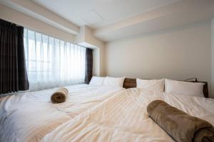 a large white bed in a room with a window at Shizuk+O Stay in Sapporo