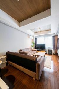 a living room with a couch and a television at Shizuk+O Stay in Sapporo