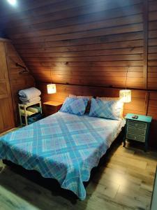 ein Schlafzimmer mit einem Bett und einer Holzwand in der Unterkunft Linda Chacara com 2 Chalés em Boituva in Boituva