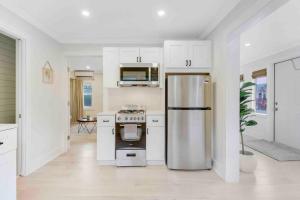 a kitchen with white cabinets and a stainless steel refrigerator at Charming Cottage on Croton #1 in West Palm Beach
