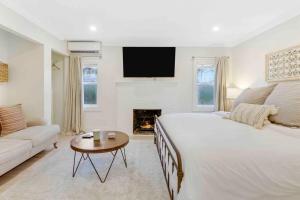 a white bedroom with a large bed and a fireplace at Charming Cottage on Croton #1 in West Palm Beach