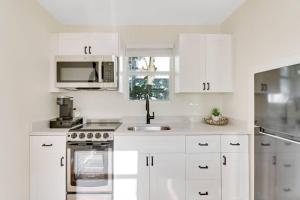 a white kitchen with a sink and a microwave at Cottage on Croton Way # 2 in West Palm Beach