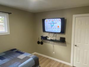 a bedroom with a flat screen tv on the wall at Bellaire Midtown Cottage in Bellaire